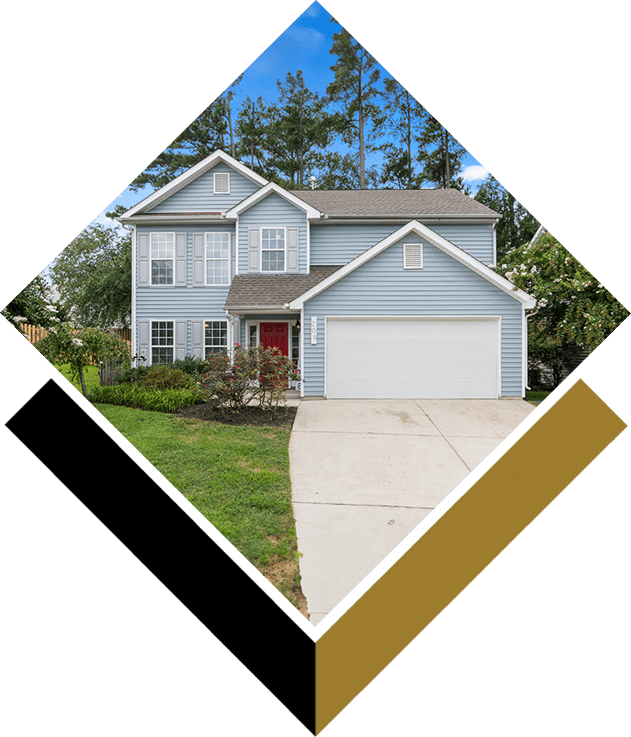 A house with a driveway and trees in the background