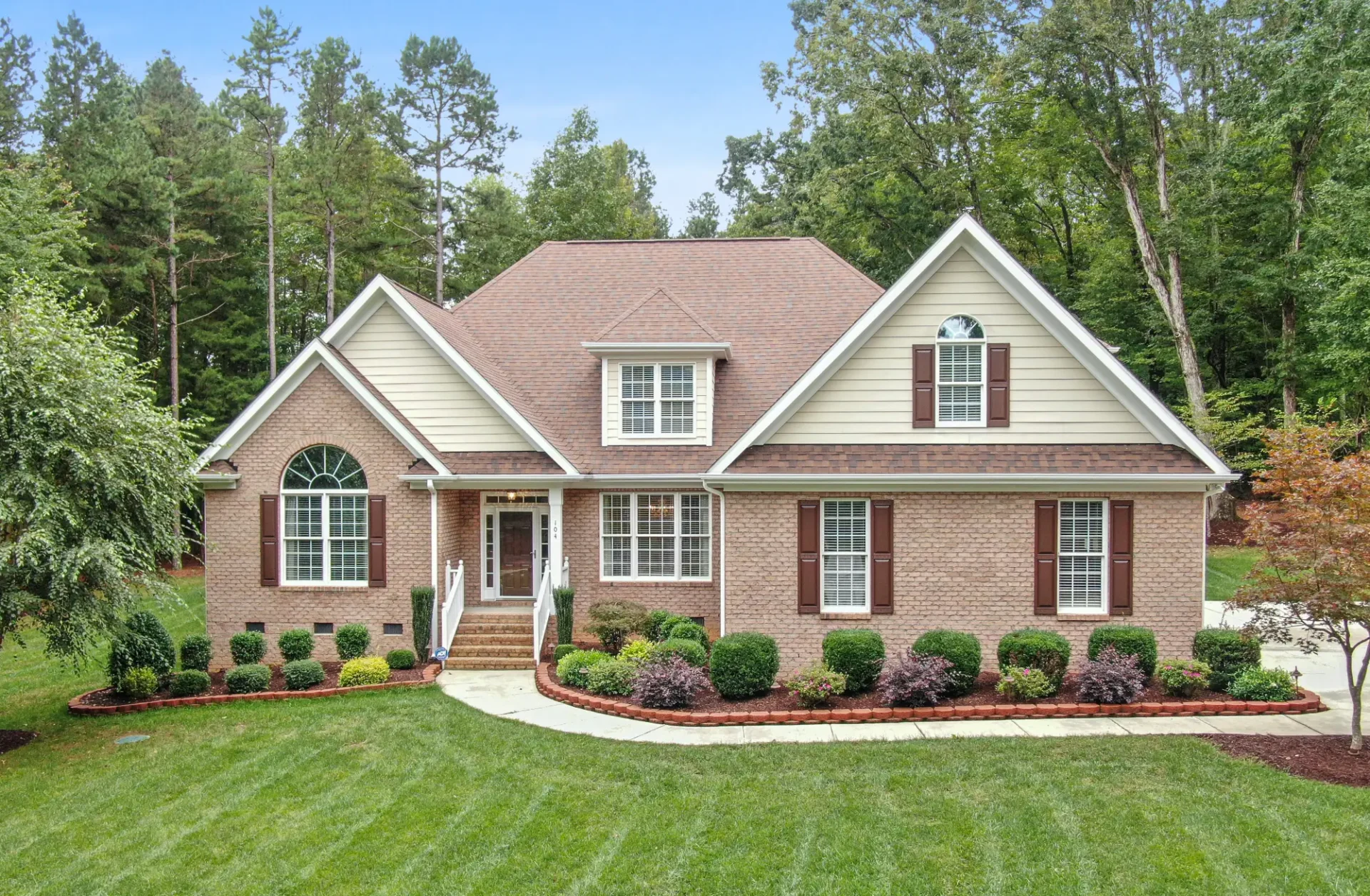 A large brick house with a lush green lawn.