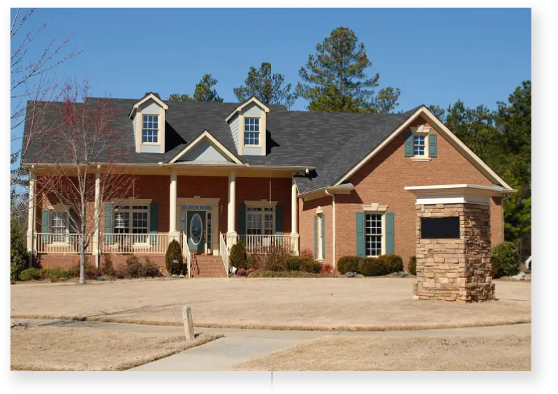 A large brick house with a stone driveway.